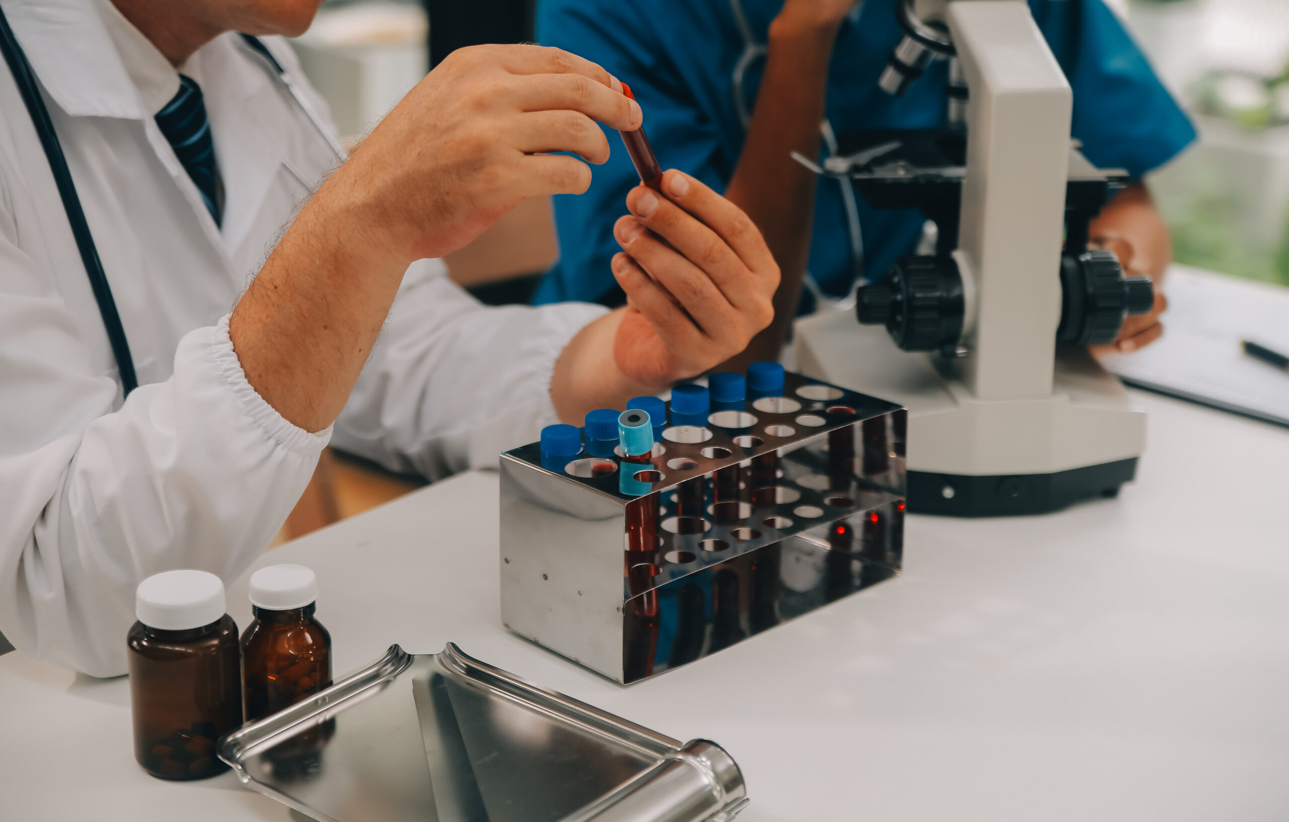 Medical worker in lab coat and sterile mask, doing a microscope for quality check of supplements
