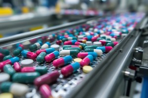 Supplements manufacturing, Conveyor belt at a pharmaceutical factory filled with multicolored capsules, drug production