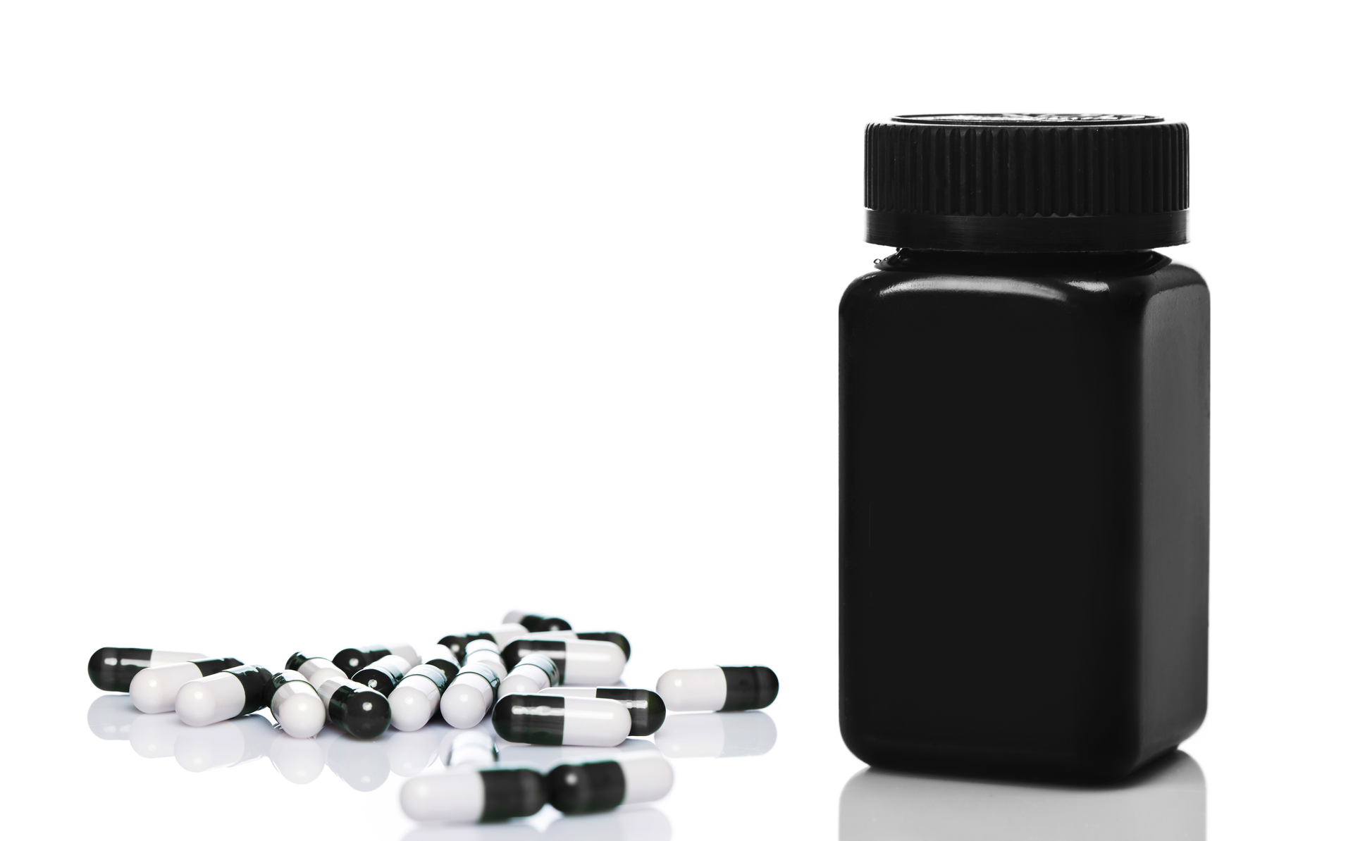 Dietary or sport supplements. Black plastic jar and capsules on white background private label supplements