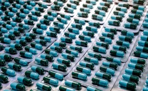 High-speed capsule manufacturing process with green capsules being sealed in blister packaging on an automated pharmaceutical production line.