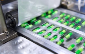 High-speed capsule manufacturing process with green capsules being sealed in blister packaging on an automated pharmaceutical production line.