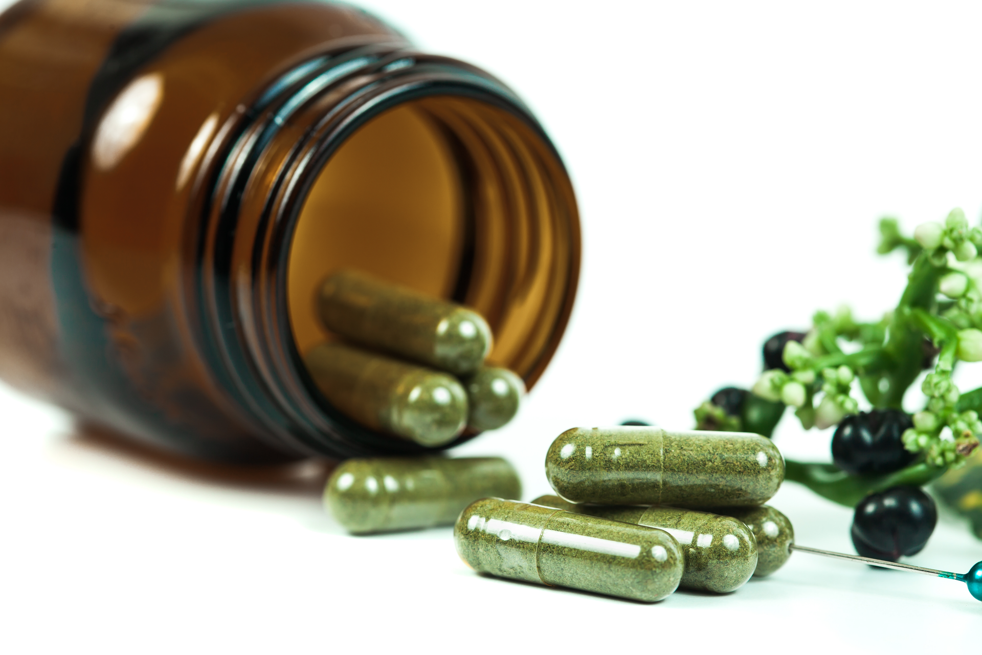 Private label herbal supplements – green plant-based capsules spilling from an amber glass bottle, symbolizing natural wellness and holistic health solutions