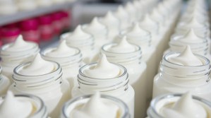 Rows of white cream jars perfectly aligned in a manufacturing setting – illustrating the foundation of a Private Label Brand for Success in the skincare and cosmetic industry.