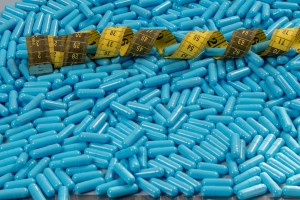 Capsule Contract Manufacturing – blue weight loss capsules with a yellow measuring tape, symbolizing slimming supplements produced by contract manufacturers in the USA