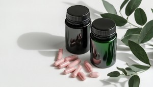 Keto Supplement Manufacturer – glossy dark bottles with pink capsules on a white surface, representing premium keto dietary supplement production with clean, minimalist packaging