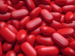 Close-up image of red coated capsules manufactured by a pharmaceutical-grade supplement and vitamin producer, emphasizing quality and consistency in tablet production