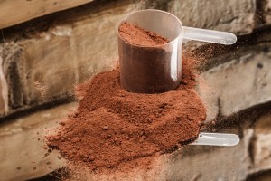 Brown powder with scoop, related to custom powder manufacturers and pre workout supplement manufacturers. Demonstrates aspects of custom powder manufacturing