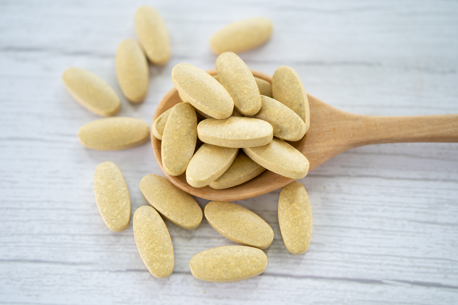 Vitamin tablets on a wooden spoon from trusted Nutrition Supplements Wholesale Suppliers offering bulk health supplements for retailers and brands