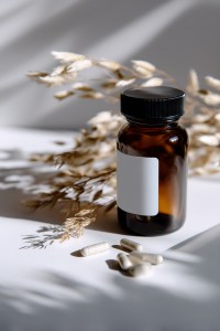 Amber glass bottle with white capsules and natural dried plants, ideal for organic supplement packaging and Vitamin Private Labeling in natural health products.
