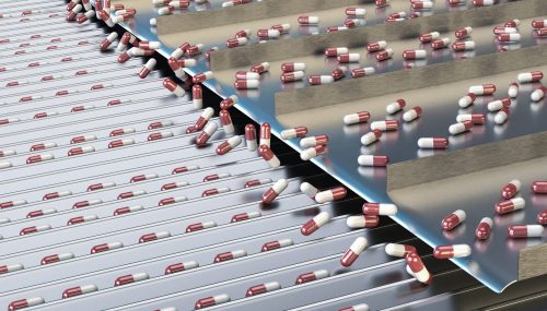 Automated supplement manufacturing process with red and white capsules on a high-speed conveyor system. Advanced dietary supplement manufacturing ensuring precision, GMP compliance, and large-scale food supplement production with rigorous quality control