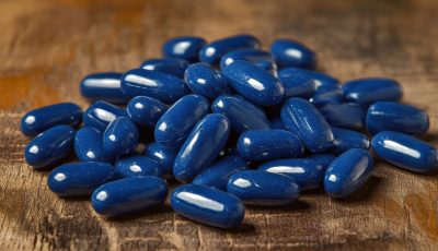 Blue softgel capsules scattered on a wooden surface, representing precision and quality by a leading softgel supplements manufacturer and private label softgel supplements provider